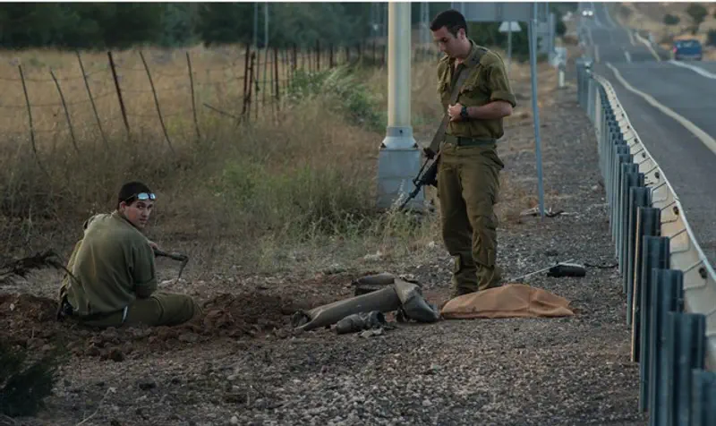 Soldiers collecting remains of rocket fired from Syria into Israel, Golan Hts