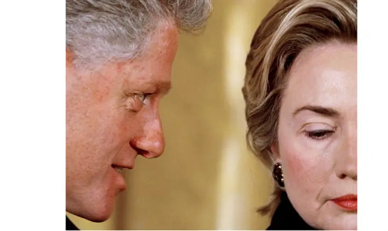 Clinton whispers to first lady Hillary Clinton during White House event