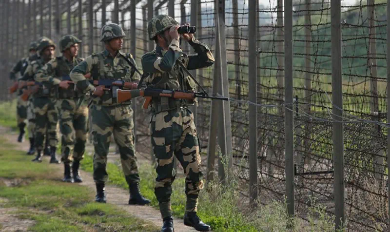 India's Border Security Force soldiers patrol fenced border with Pakistan
