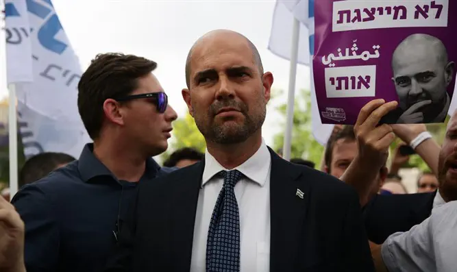 השר אמיר אוחנה עם השלטים שהונפו נגדו