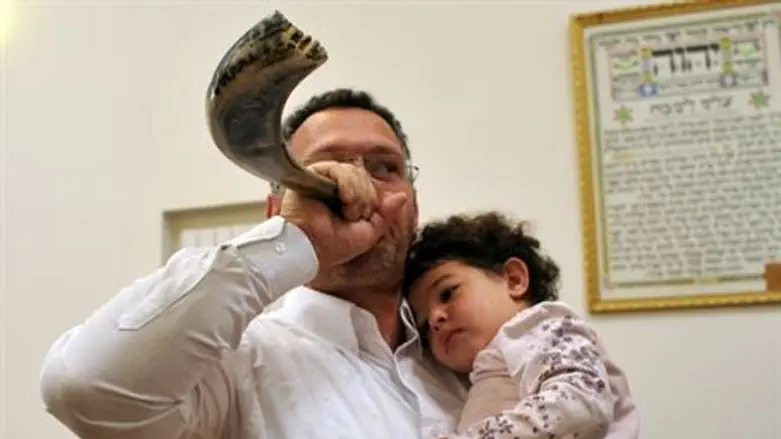 Father blows the shofar with his child
