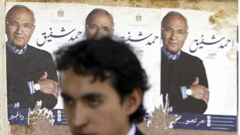 Man walks past campaign posters for Ahmed Sha