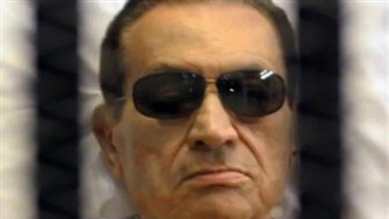 Mubarak sits inside a cage in a courtroom