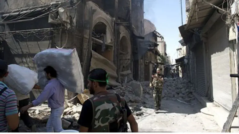 Syrian civilians walk past the rubble of buil