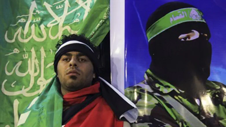 man poses next to poster of Hamas terrorist