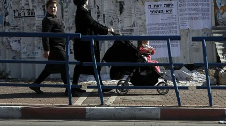 Women walk by signs praising modesty in Beit 