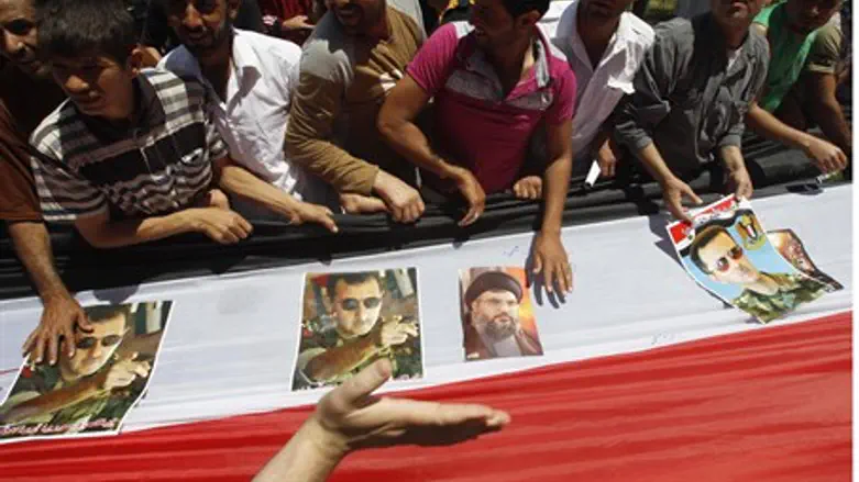 Syrians carry flag with pictures of Syria's a