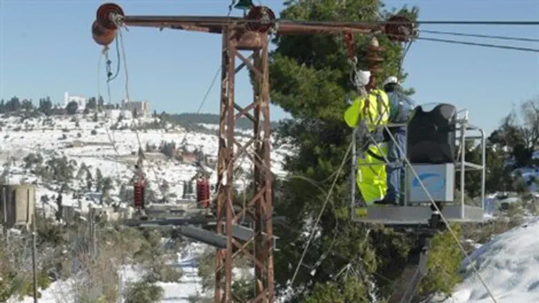 עובדי חברת חשמל מתקנים קווי מתח בשלג