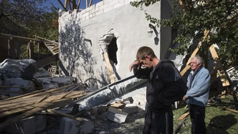 A man reacts near a house damaged by shelling