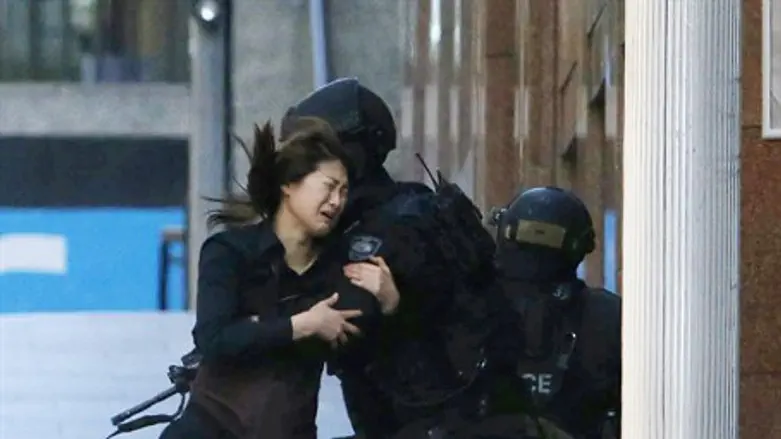 A hostage runs towards a police officer outside Lindt cafe, where other hostages are being