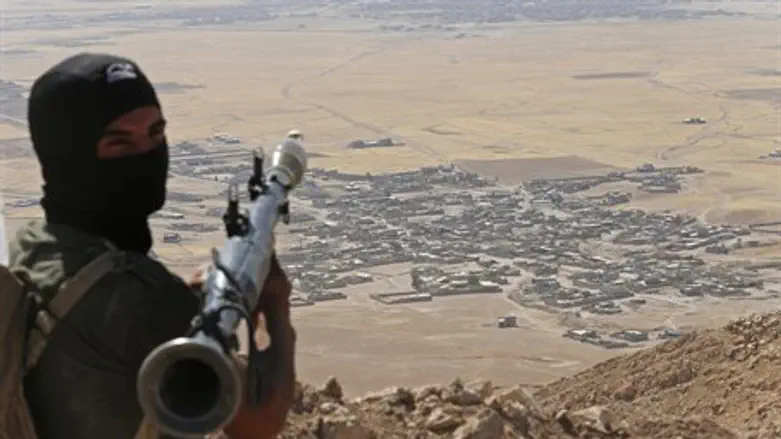 A Kurdish fighter hold a position overlooking IS-controlled territory in Iraq