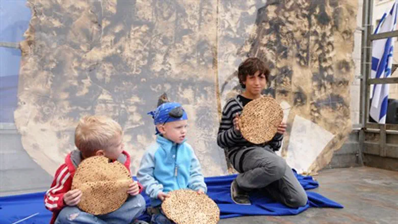 Israeli children eat matza at a Meir Panim center