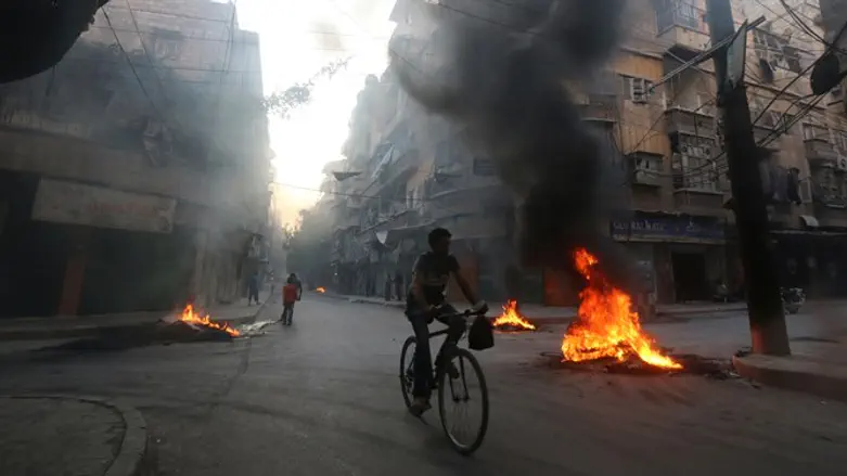 A man rides past burning tires, which activists said are used to create smoke cover