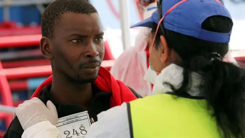 Medical staff member checks the condition of migrant as they arrive at Crotone harbour. It