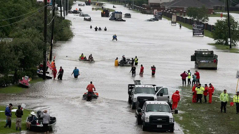 Houston residents and rescuers make their way out of a flooded neighborhood after it was i