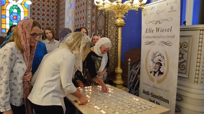 Women lighting a candle in memory of Elie Wiesel at the synagogue of Ordea in northern Rom