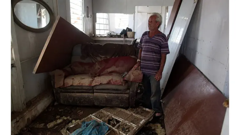 Man stands in rubble of house damaged by Hurricane Maria
