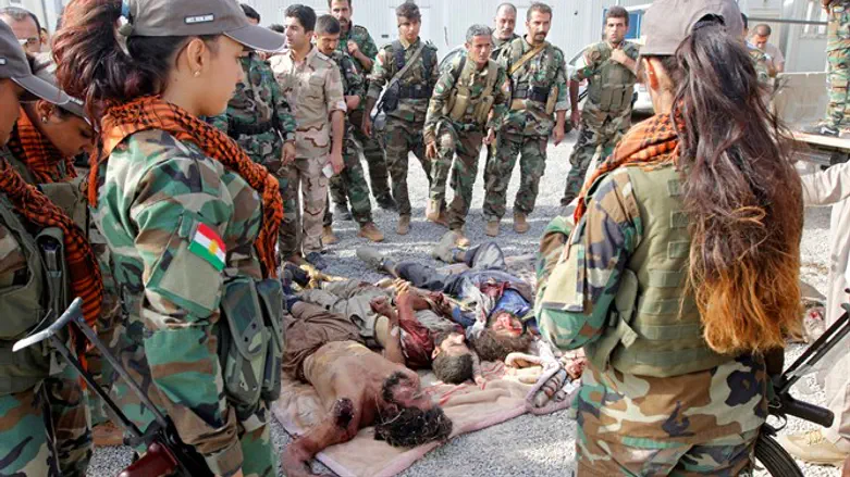 Kurdish Peshmerga fighters stand by the bodies of ISIS terrorists killed near Kirkuk