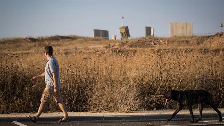 Man walks dog past Iron Dome battery near Sderot, Israel