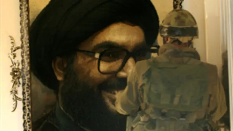 IDF soldier looks at portrait of Nasrallah in Lebanese