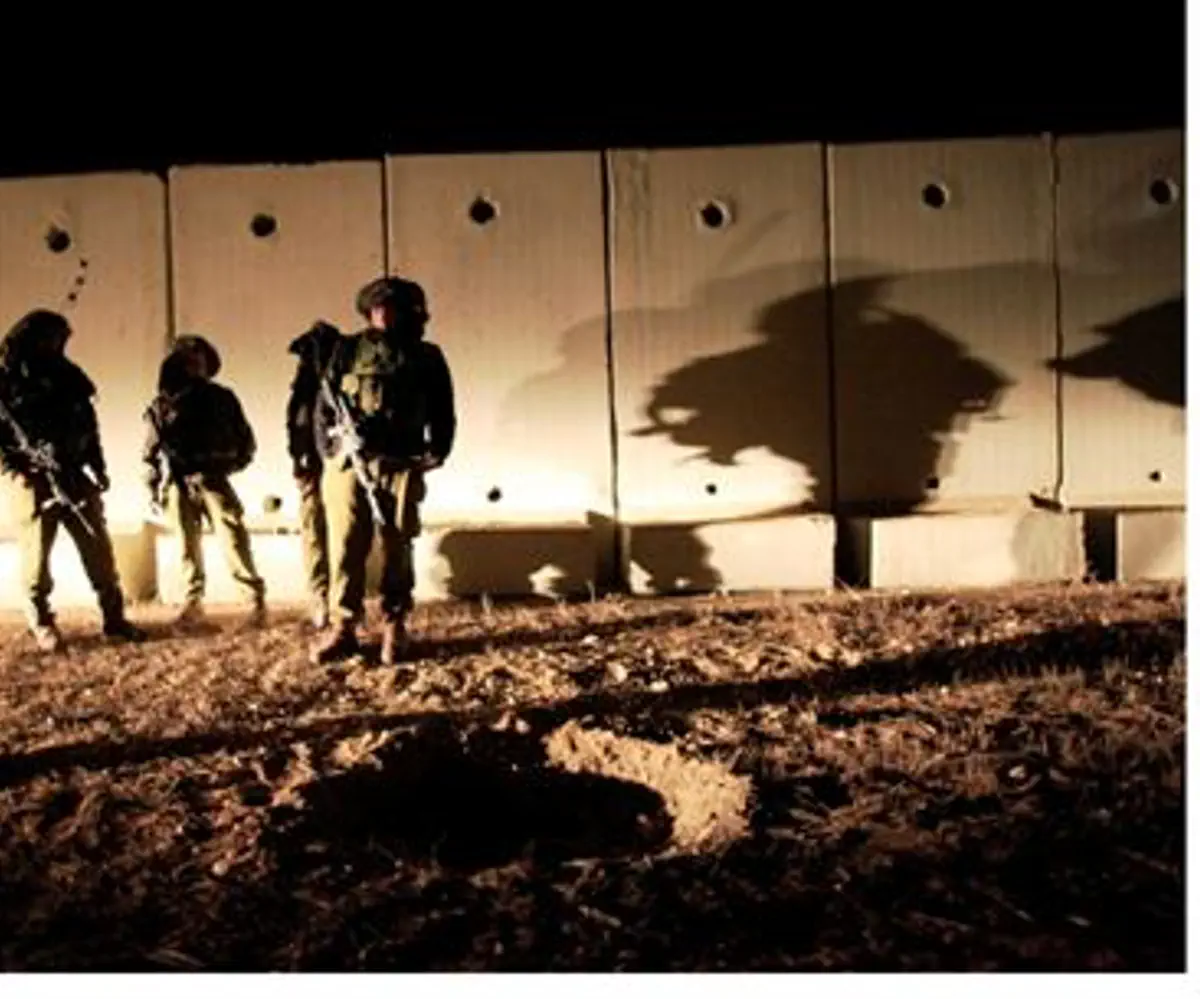 IDF troops view crater created by shell