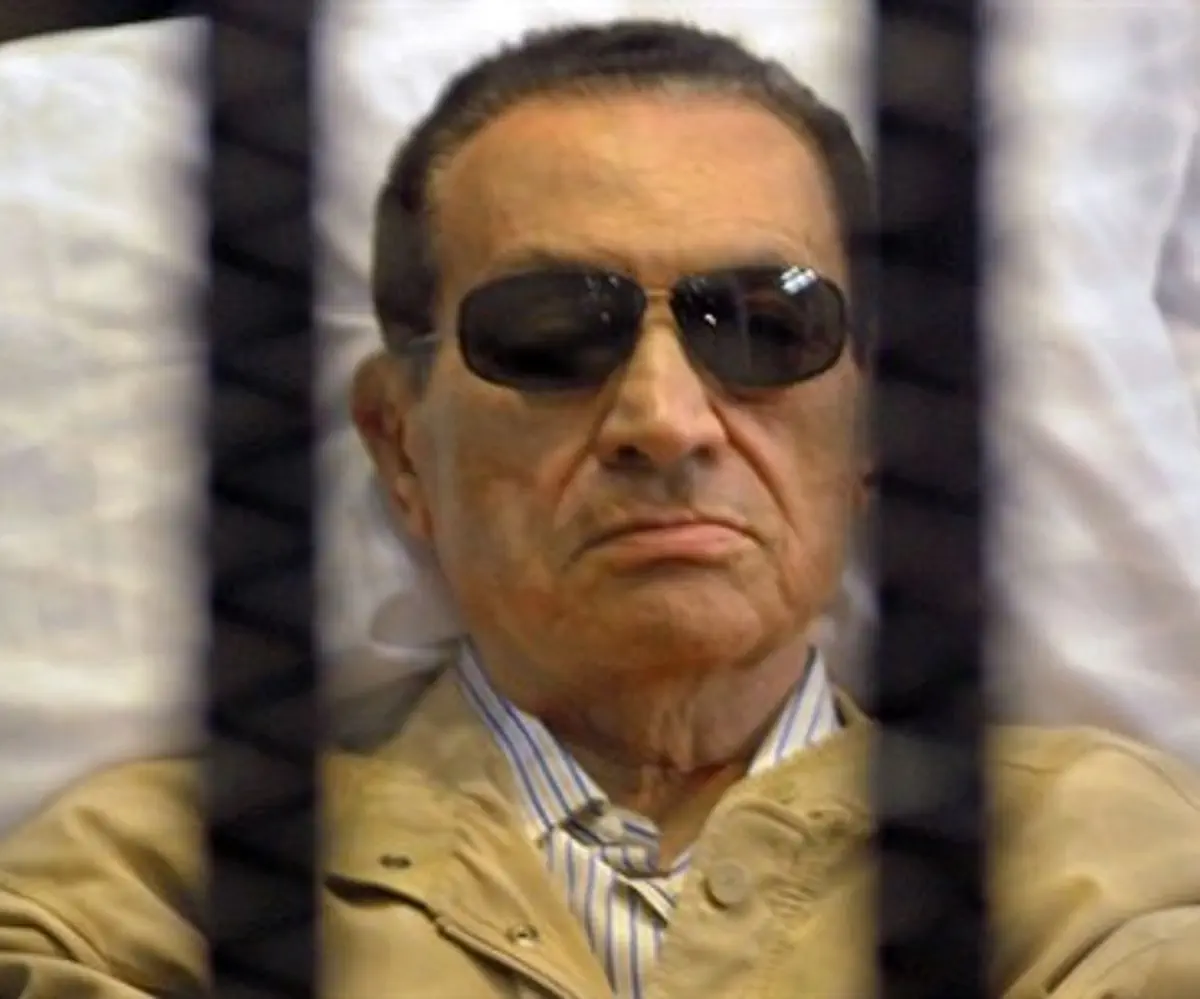 Mubarak sits inside a cage in a courtroom 