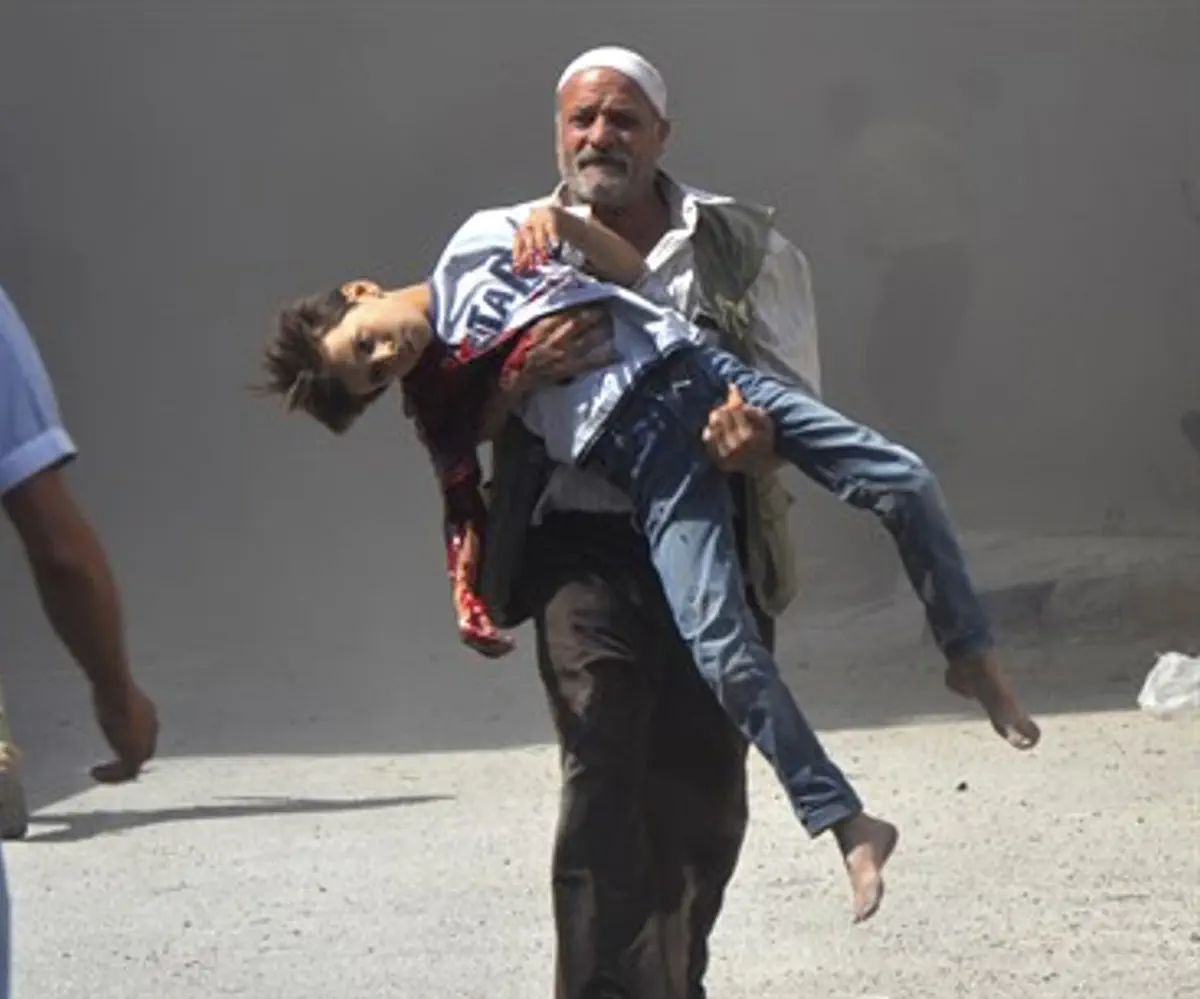 Syrian man carries wounded boy (illustration)