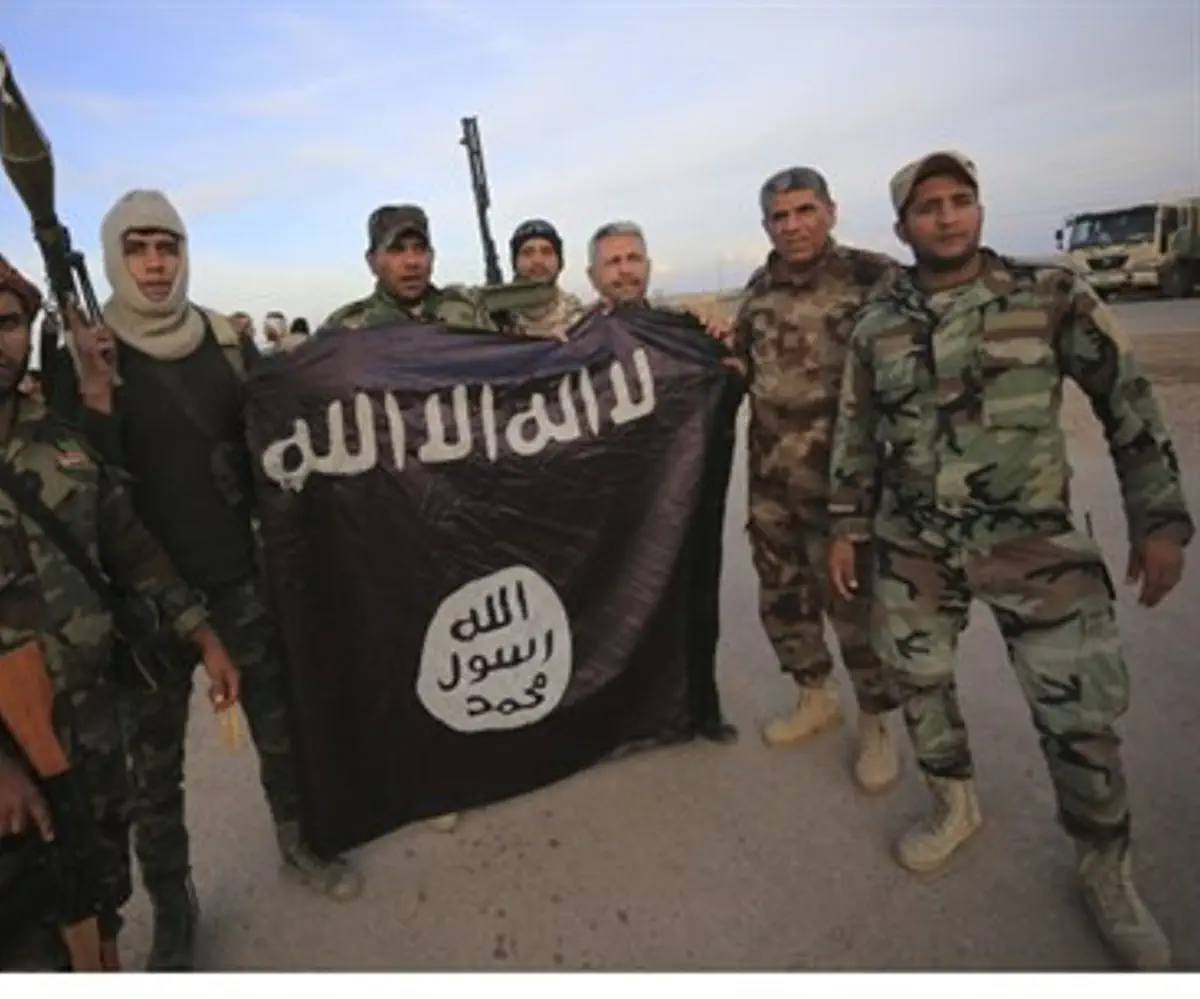 Iraqi Shi'ite fighters pose with captured ISIS flag
