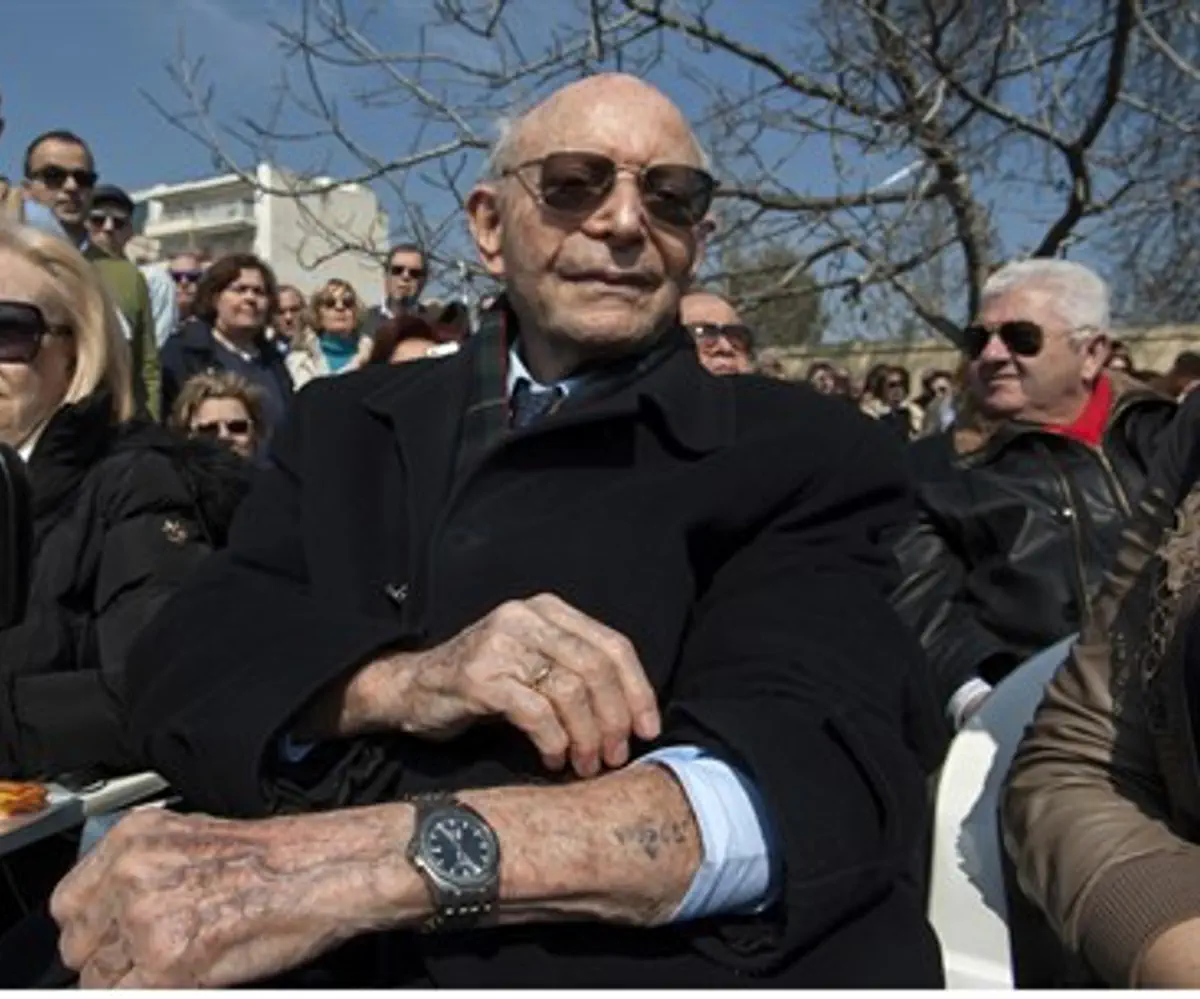 Holocaust survivor Heinz Kounio shows the tattoo he received at Auschwitz