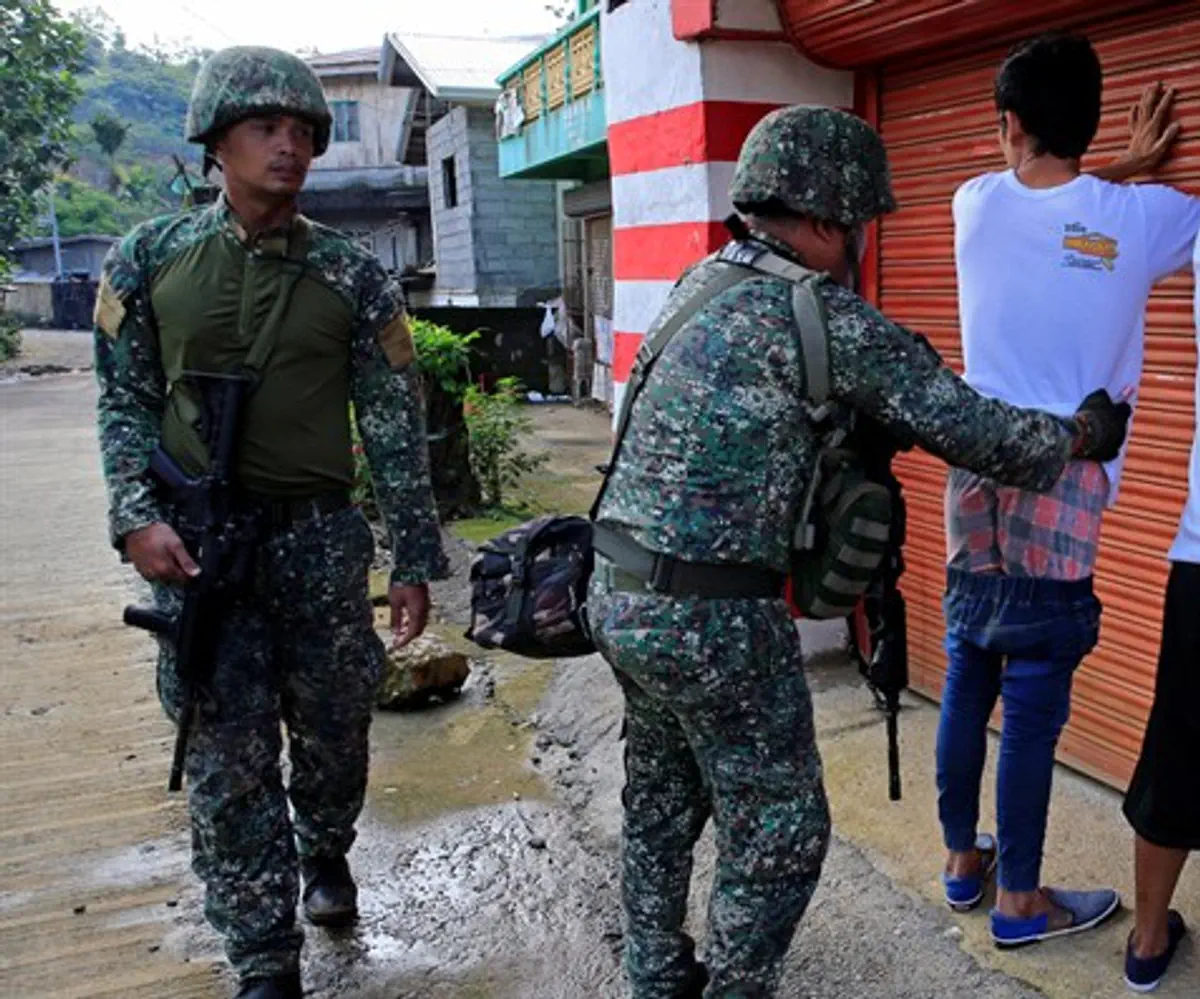 Government soldier frisks resident who evacuated his home in Sarimanok village, Marawi