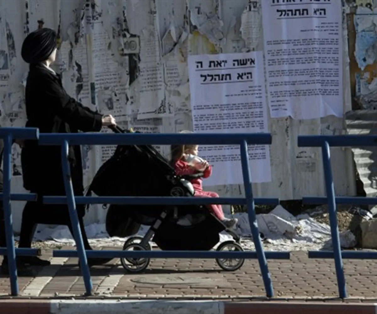 Women walk by signs praising modesty in Beit Shemesh