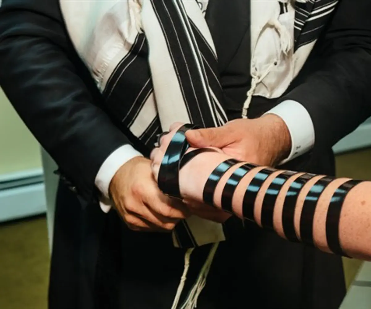 Chabad emissary assisting in donning tefillin