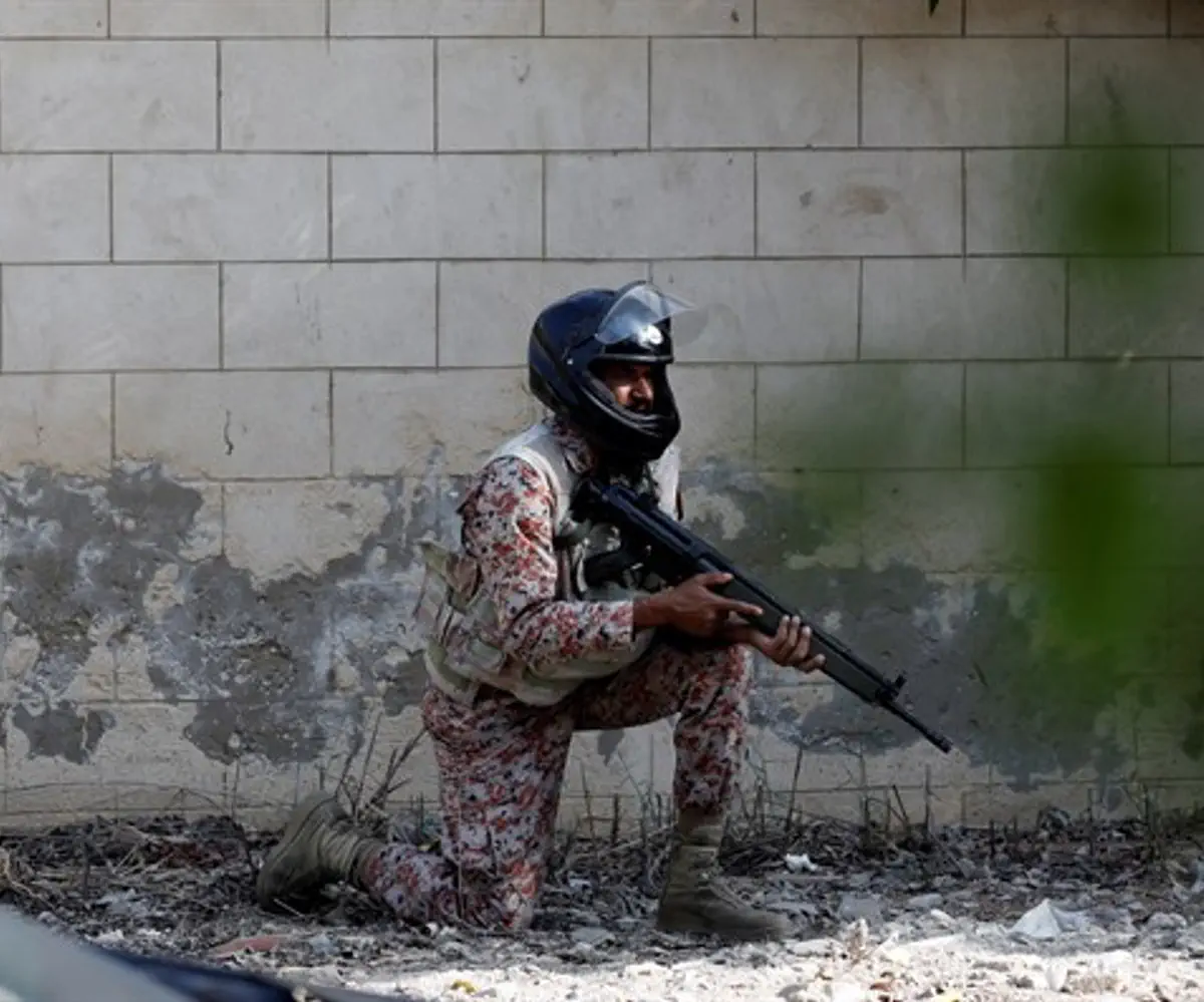 Pakistani soldier crouches behind wall during Chinese embassy attack