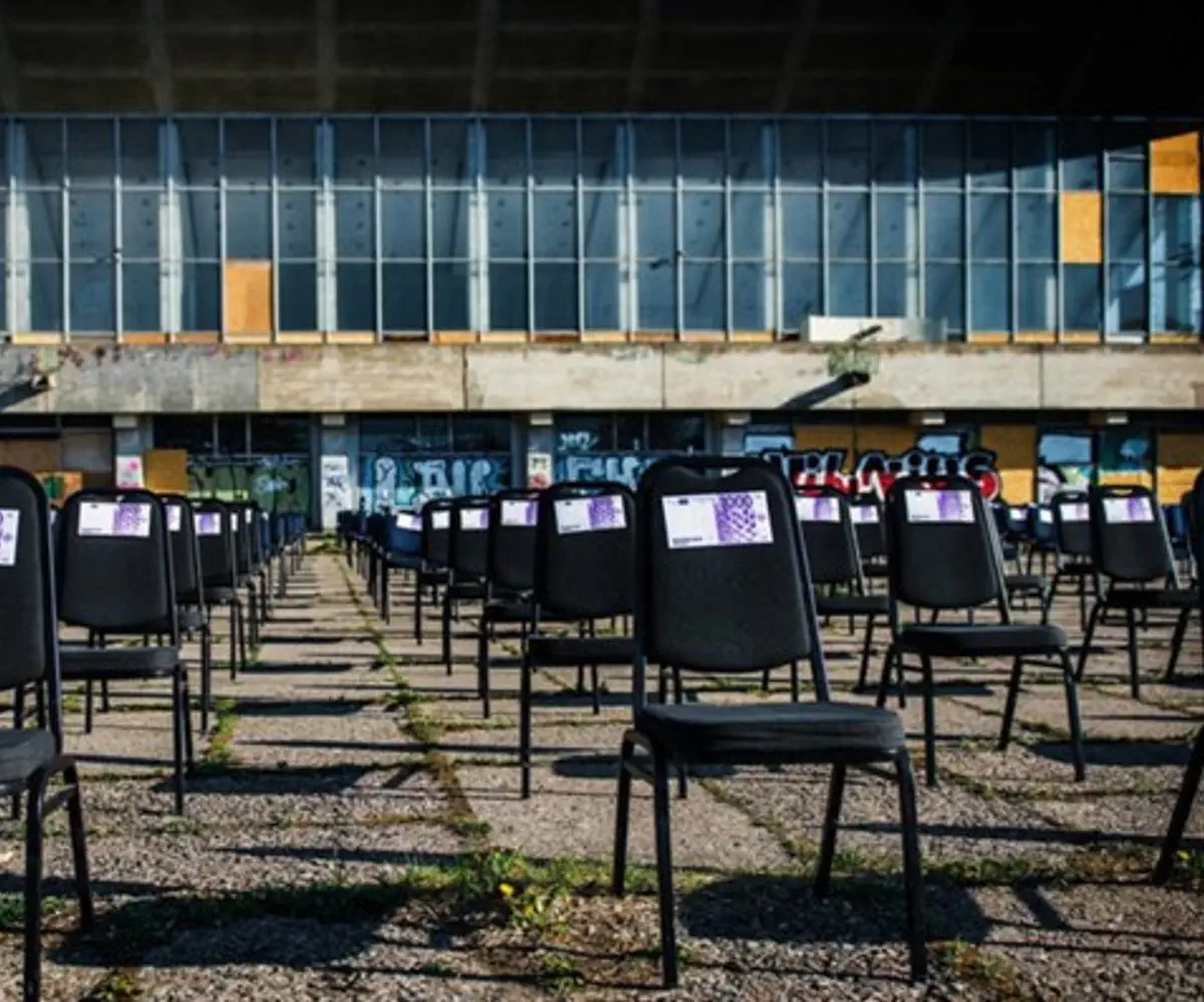 Chairs with fake money next to decaying Palace of Concerts & Sports of Vilnius