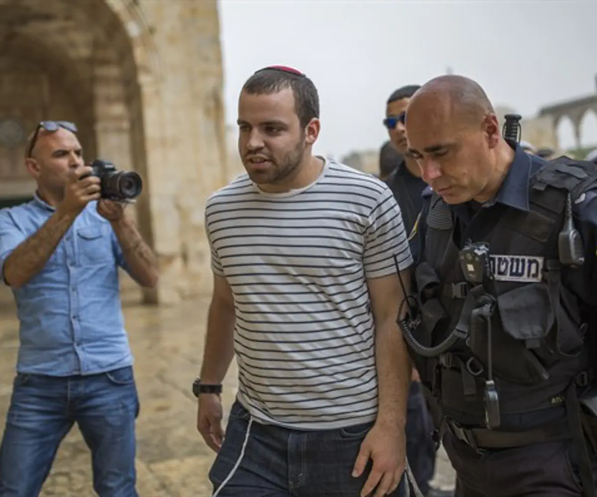 A Waqf guard (L) monitors Jewish visitors to the Temple Mount