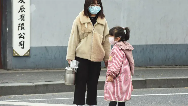 אישה וילדה בסין עם מסכות להגנה מפני הוירוס
