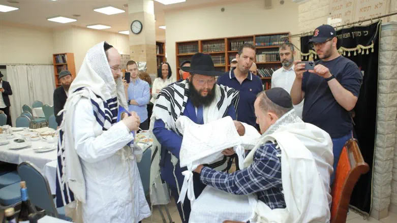 Rabbi Shalom Ber Stambler presents the baby to the “Sandek” Mr. Yochanan Michael