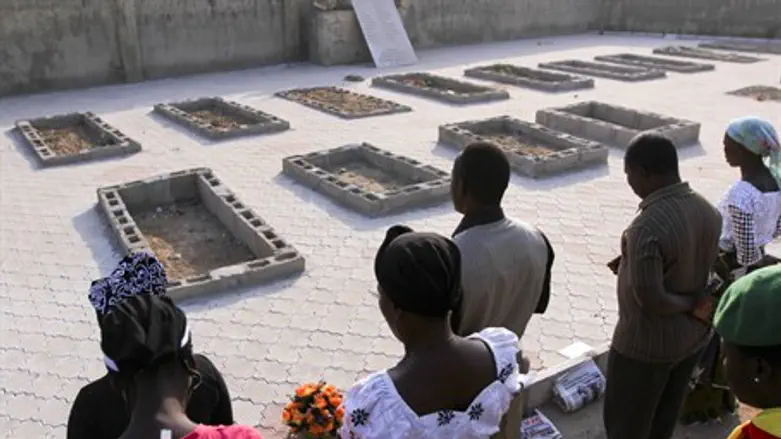 People pray near the graves of victims of an 
