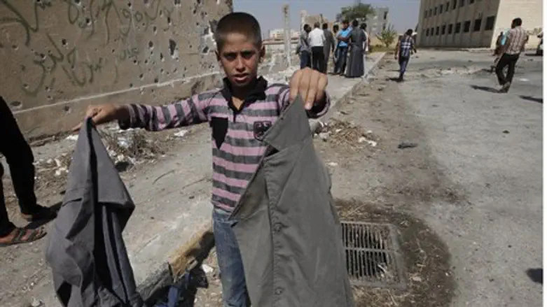 Syrian child holds school uniforms at the sit