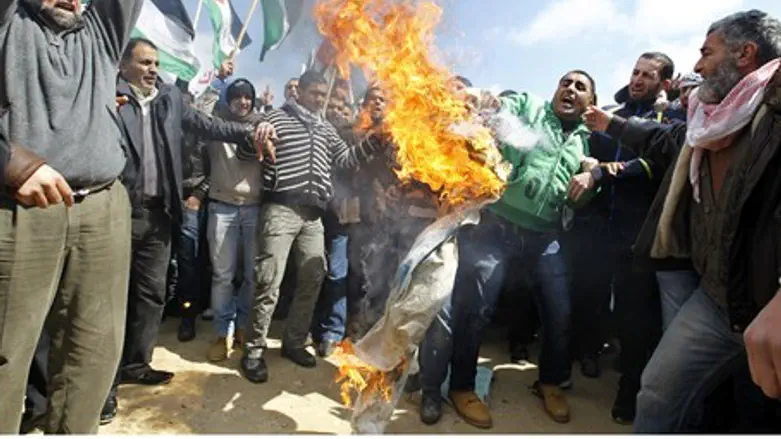 Protesters burn an Israeli flag near the Isra