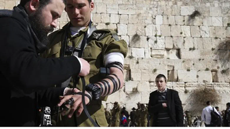Soldier puts on tefillin at the Kotel (file)