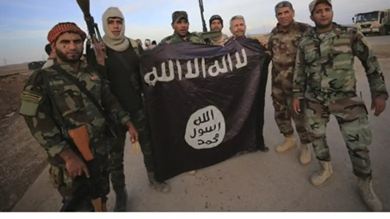 Iraqi Shi'ite fighters pose with captured ISIS flag