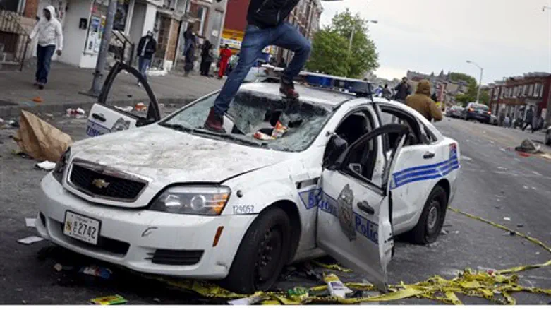 Rioters destroy a police car in Baltimore