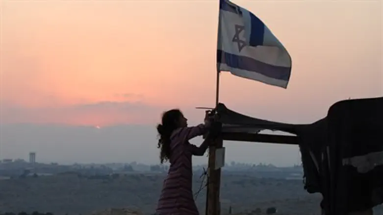 Jewish girl raises Israeli flag at the Israeli village of Avnei Hefetz, Samaria
