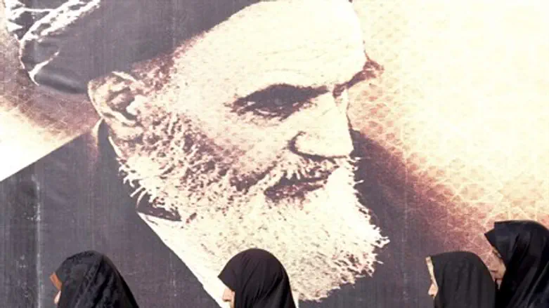 Iranian women by a poster of Ayatollah Khomeini