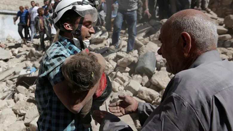 A child's body is carried away fromthe site of a regime bombing in Idlib, Syria
