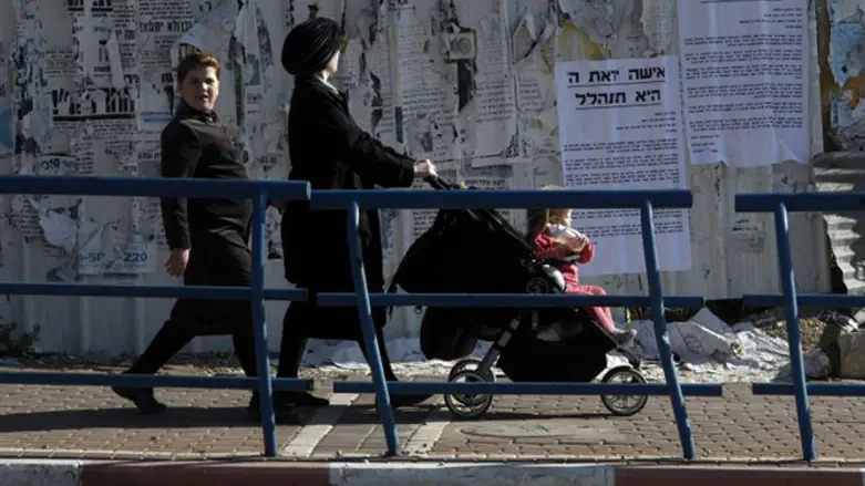 Women walk by signs praising modesty in Beit Shemesh