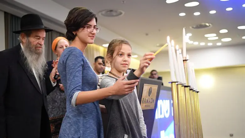 Ruth Zagha lights the 8th candle with Reut Salomon at the Colel Chabad Chanuka Retreat in 