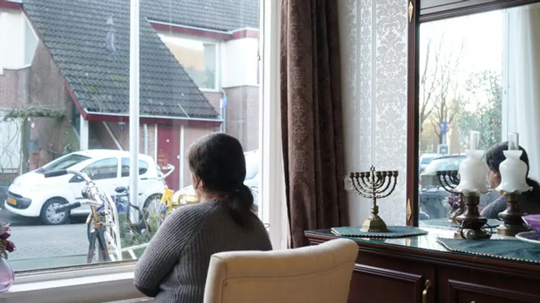 Sipora, a Jewish refugee from Iran, looking out the window of her daughter's Netherlands h