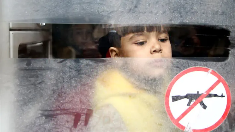 Boy looks out bus window during evacuation of Douma